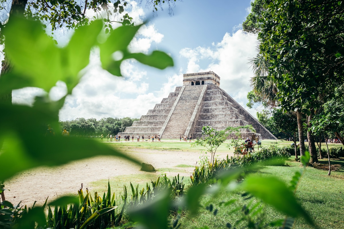 El Castillo pyramid at Chichen Itza framed by green foliage, Yucatan