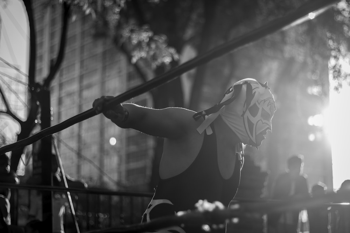 Masked lucha libre wrestler gripping the ring ropes at an outdoor fight in Mexico City