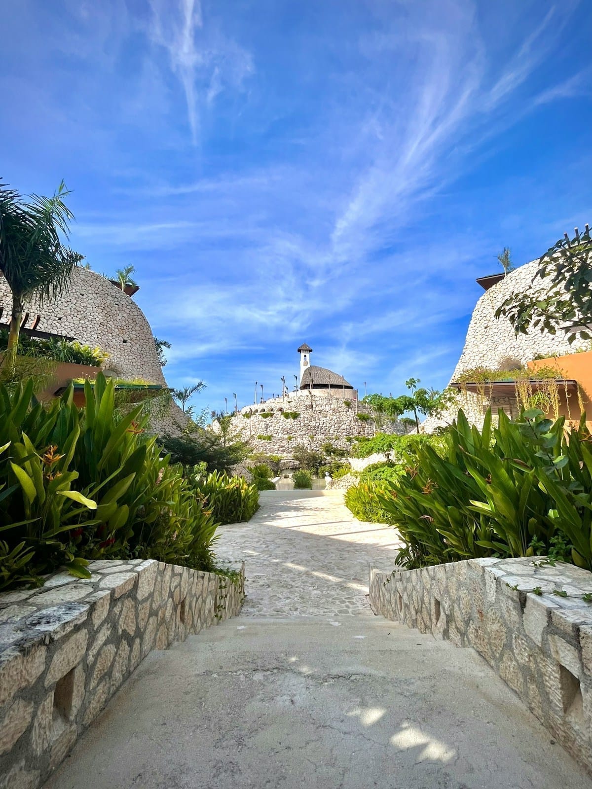 Stone walkway lined with tropical plants at Xcaret Arte, Solidaridad, Riviera Maya, Mexico