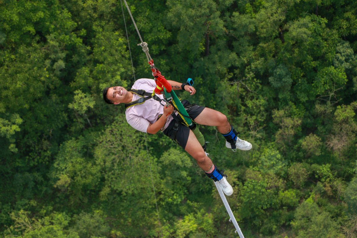 Man on a zip line in a safety harness above green jungle canopy - adventure at Xplor Park, Riviera Maya