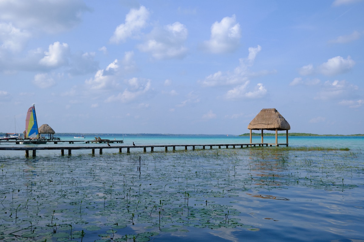 Wooden dock with thatched pavilion extending over the turquoise waters of Bacalar Lagoon, Quintana Roo, Mexico