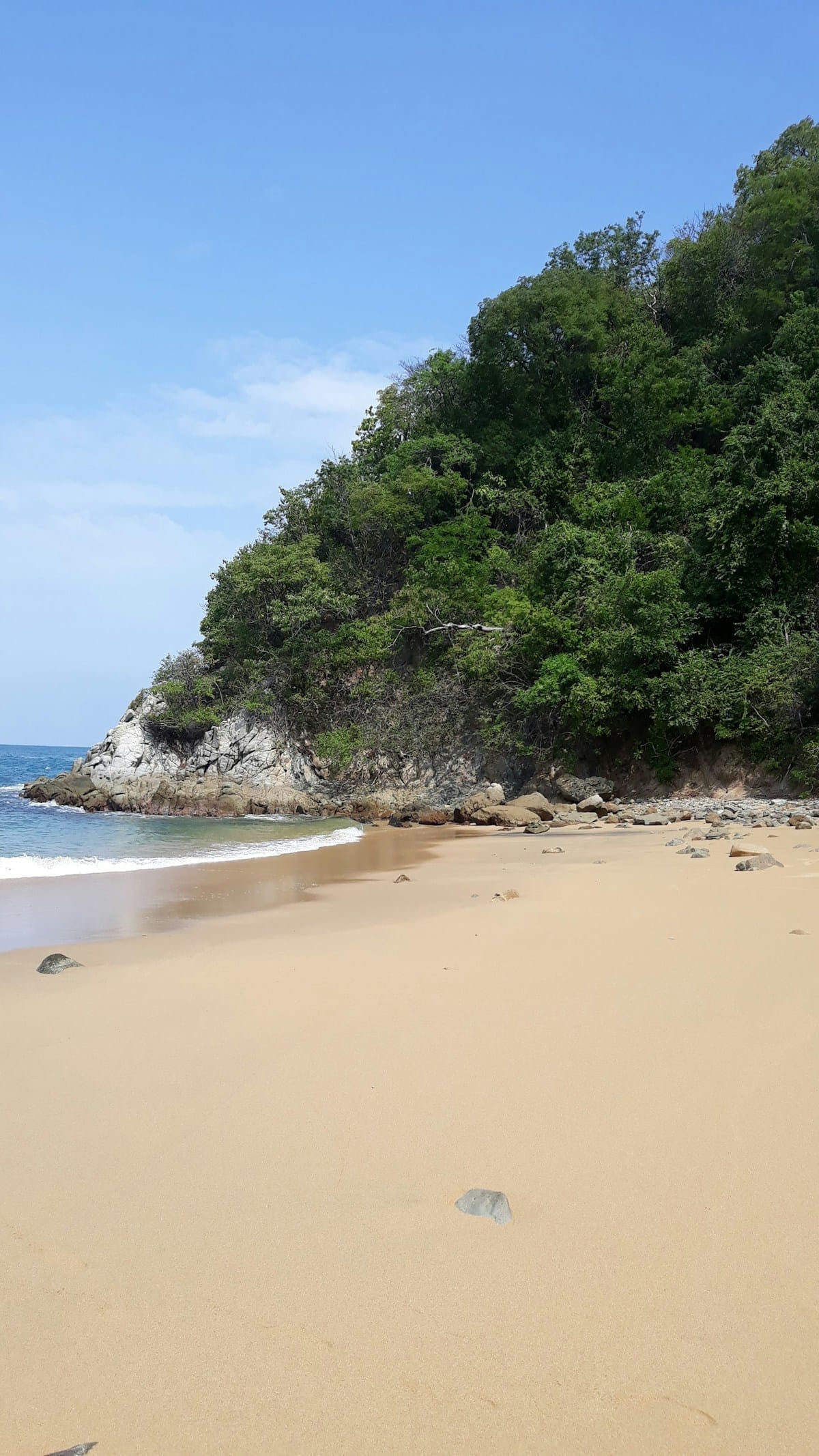 Secluded sandy beach with jungle hillside at Huatulco