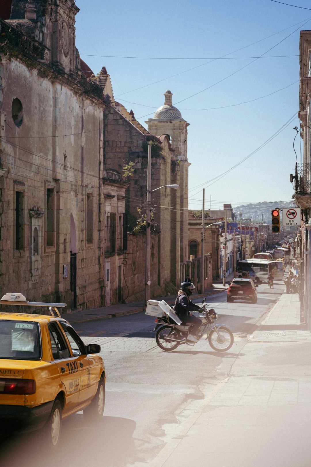Motorcyclist rides down a sunny historic street, Oaxaca, Mexico