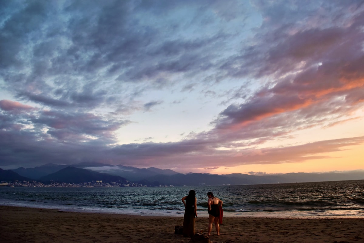 Couple watching a colourful sunset over the Pacific Ocean in Puerto Vallarta, Mexico