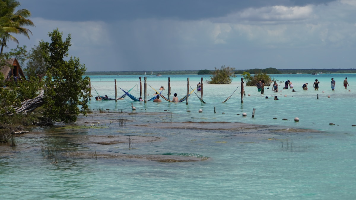 People relaxing in hammocks over turquoise water, Bacalar Lagoon, Mexico