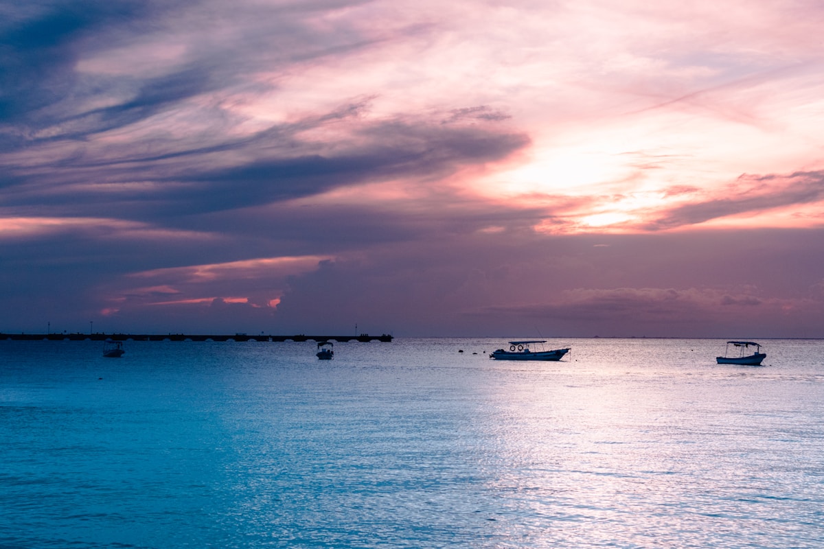 Boats moored on calm turquoise Caribbean water at sunset, Cozumel, Mexico