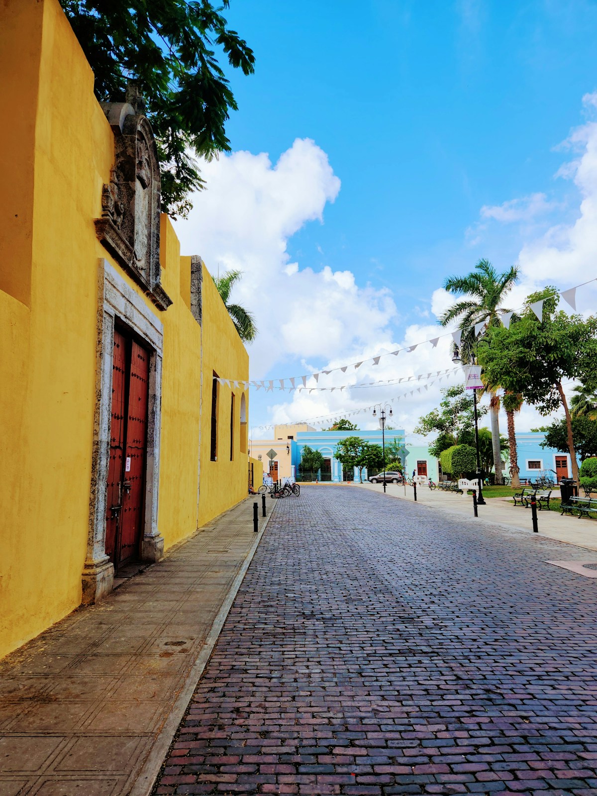 Cobblestone street lined with yellow colonial buildings, Merida, Yucatan, Mexico