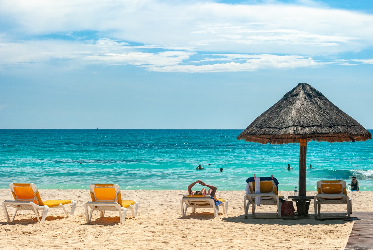 Beach loungers and palapa umbrella on turquoise Caribbean water, Cancún Hotel Zone