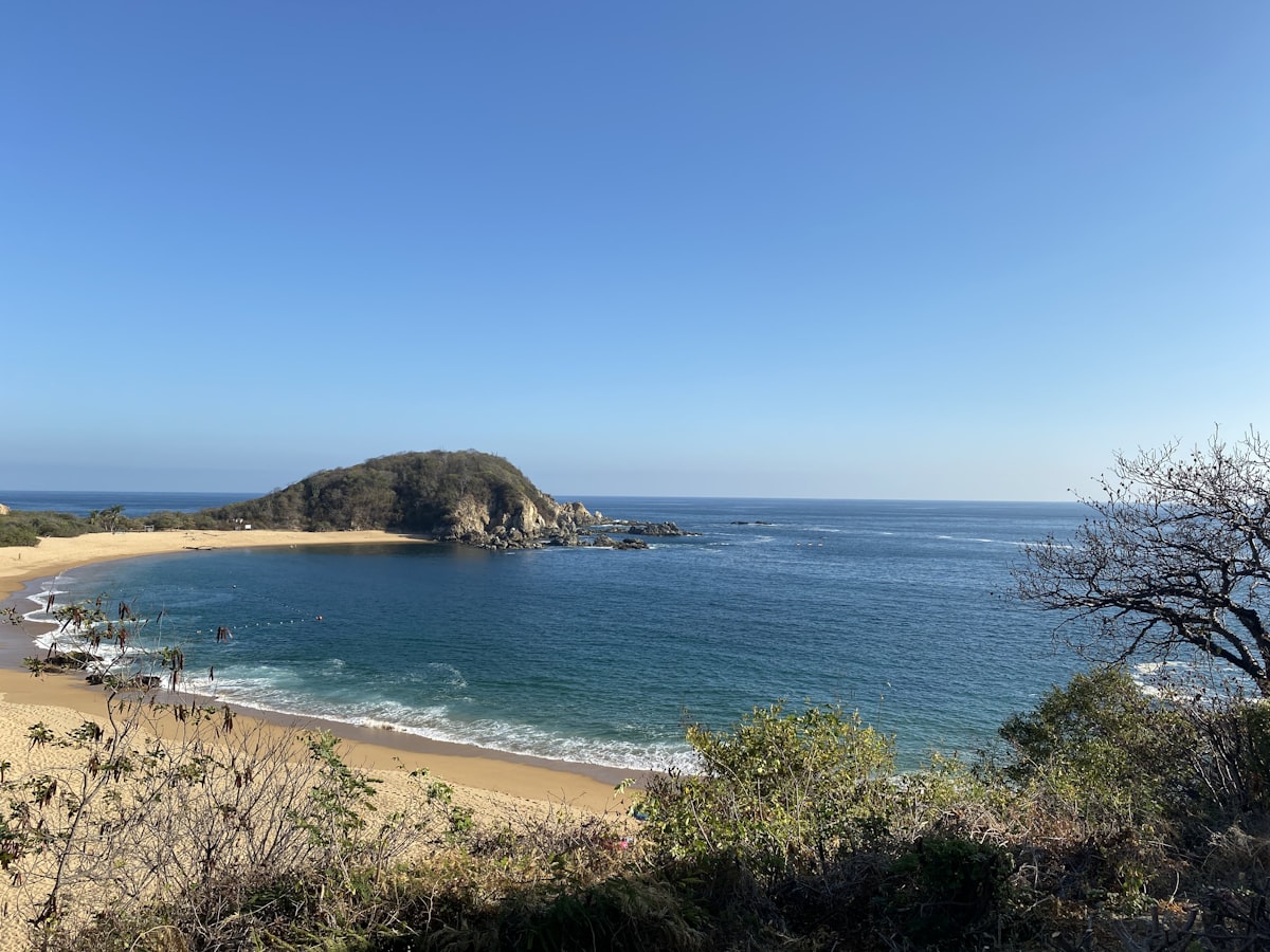 Sandy bay with clear blue water and green headland, Huatulco, Oaxaca, Mexico