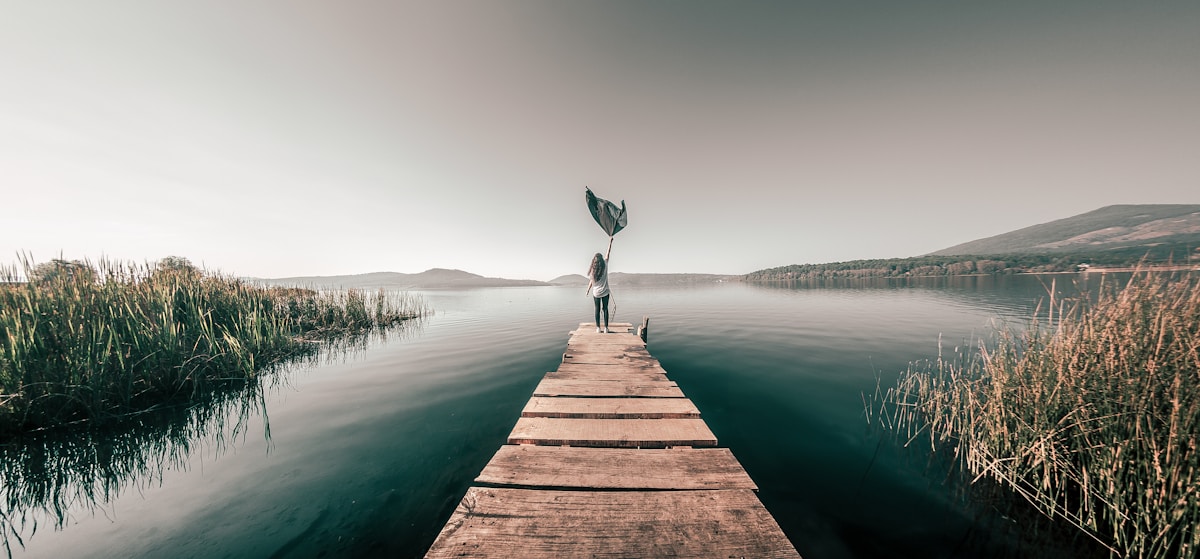 Person standing on wooden dock over calm lake, Michoacán, Mexico