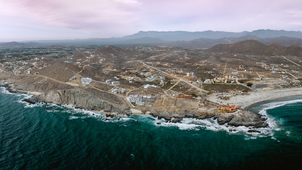 Aerial view of coastal town with Pacific Ocean waves and Sierra de la Laguna mountains, Playa Los Cerritos area near Todos Santos, Baja California Sur, Mexico